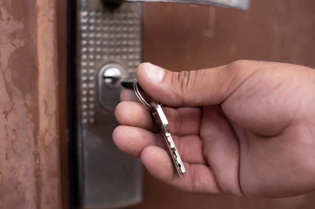 Une main insère une clé métallique dans le cylindre d'une serrure pour tester sa rotation, illustrant une étape pratique de comment entretenir le barillet d une porte serrurier paris.