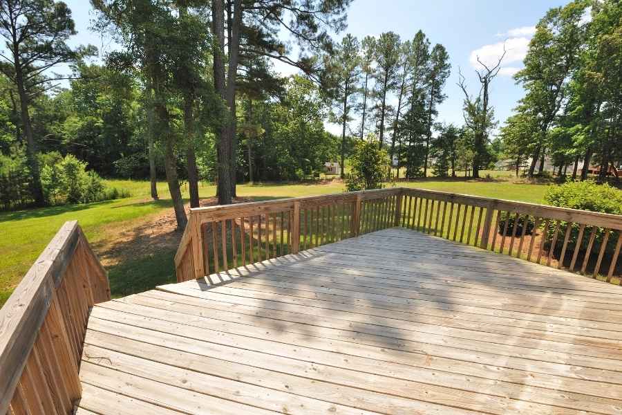 Une vaste terrasse en bois surélevée entourée d'un garde-corps et offrant une vue dégagée sur une forêt verdoyante